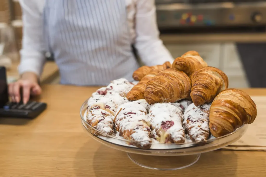 A close-up view of a cookie croissant with a flaky golden crust and gooey cookie dough filling.