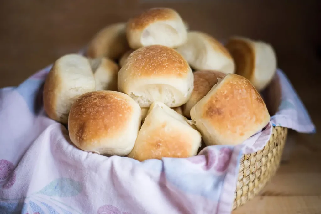 Freshly baked soft and fluffy dinner rolls on a baking tray, golden brown and ready to serve.