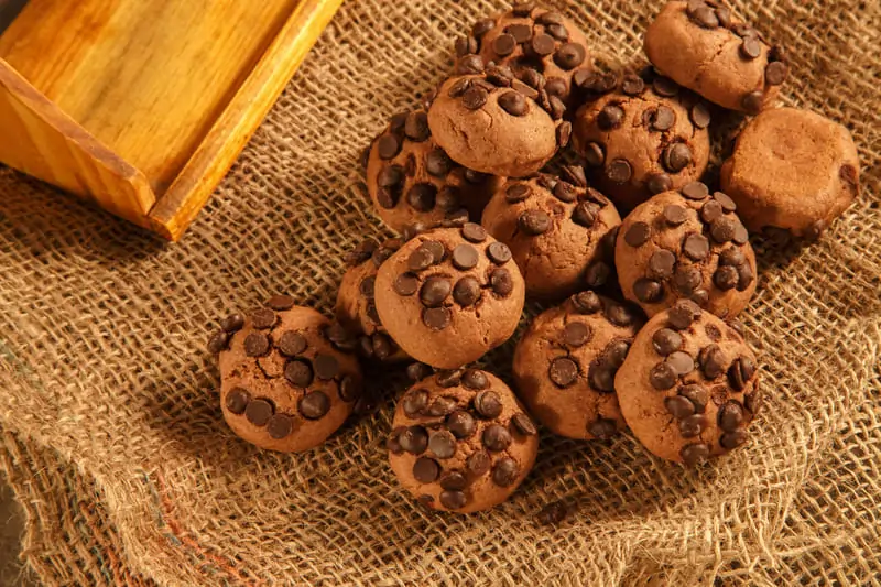 Freshly baked brownie cookies with crackly tops, fudgy centers, and crispy edges, stacked on a cooling rack with melted chocolate drizzle