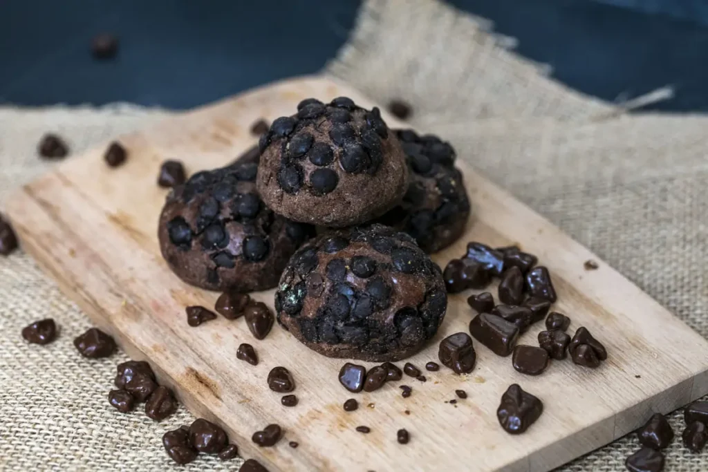 Freshly baked brownie cookies with crackly tops, fudgy centers, and crispy edges, stacked on a cooling rack with melted chocolate drizzle.